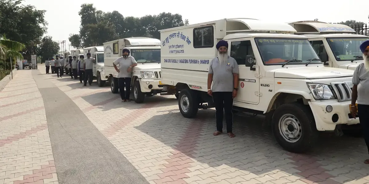 Sewadars standing with the Langar delivery vehicles at Pur Heeran